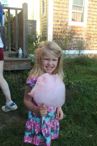 A smiling little girl holding pink cotton candy at a family Oktoberfest